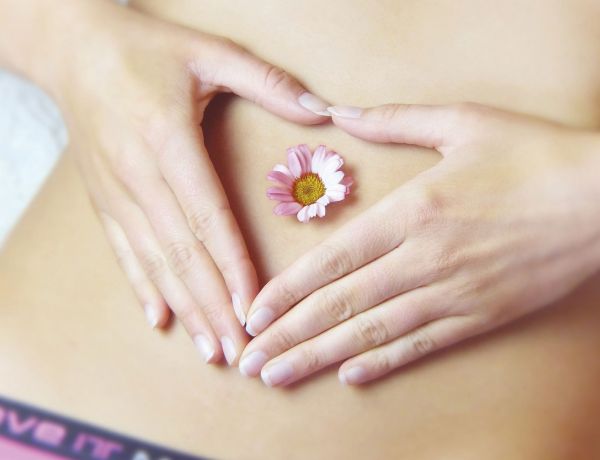 Frau legt beide Hände in Herzform auf den Bauch als Zeichen für Darmgesundheit.