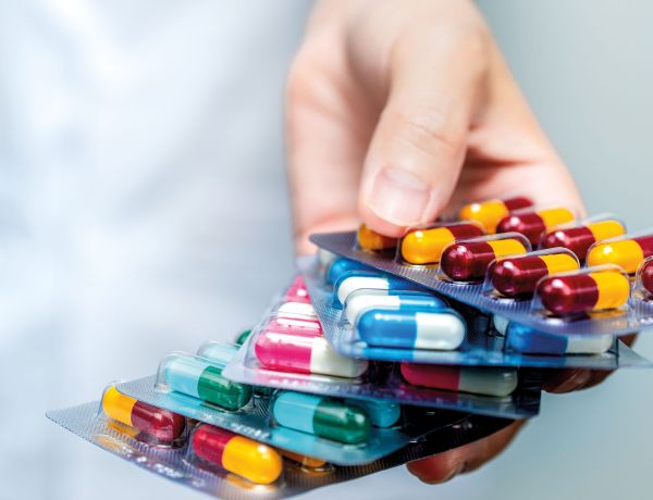 Hand hält verschiedene Tabletten und Blisterpackungen als Symbol für Arzneimittel.