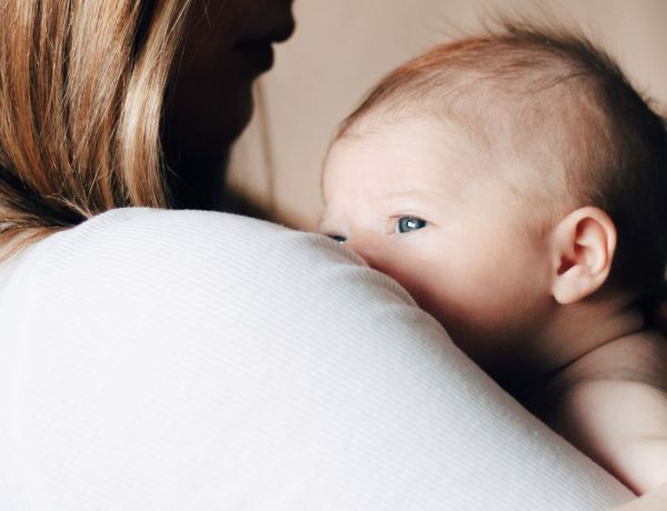 Baby schaut über Mutters Schluter