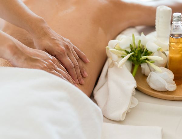 Frau liegt auf dem Bauch und erhält eine Rückenmassage mit Öl.