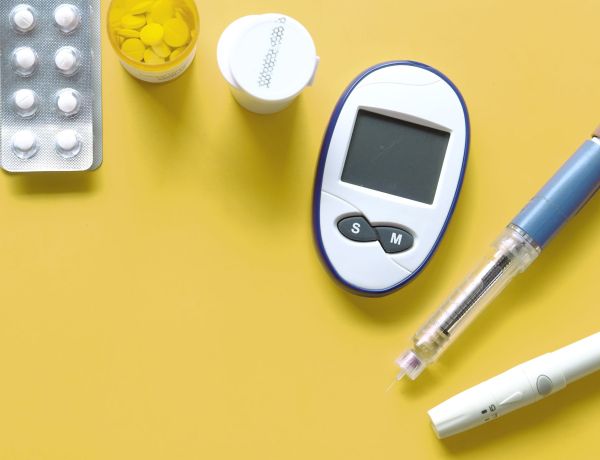 Blutzuckermessgeräte, Teststreifen und Insulinutensilien auf gelbem Hintergrund als Darstellung der Diabetes-Therapie