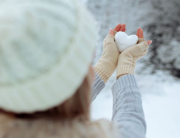 Hände mit Handschuhe halten Schnee-Herz