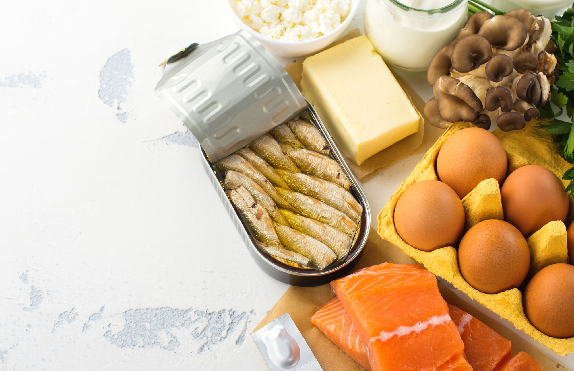Auswahl an Lebensmitteln wie Fisch, Käse, Eier und Obst als natürliche Vitamin-D-Quelle.