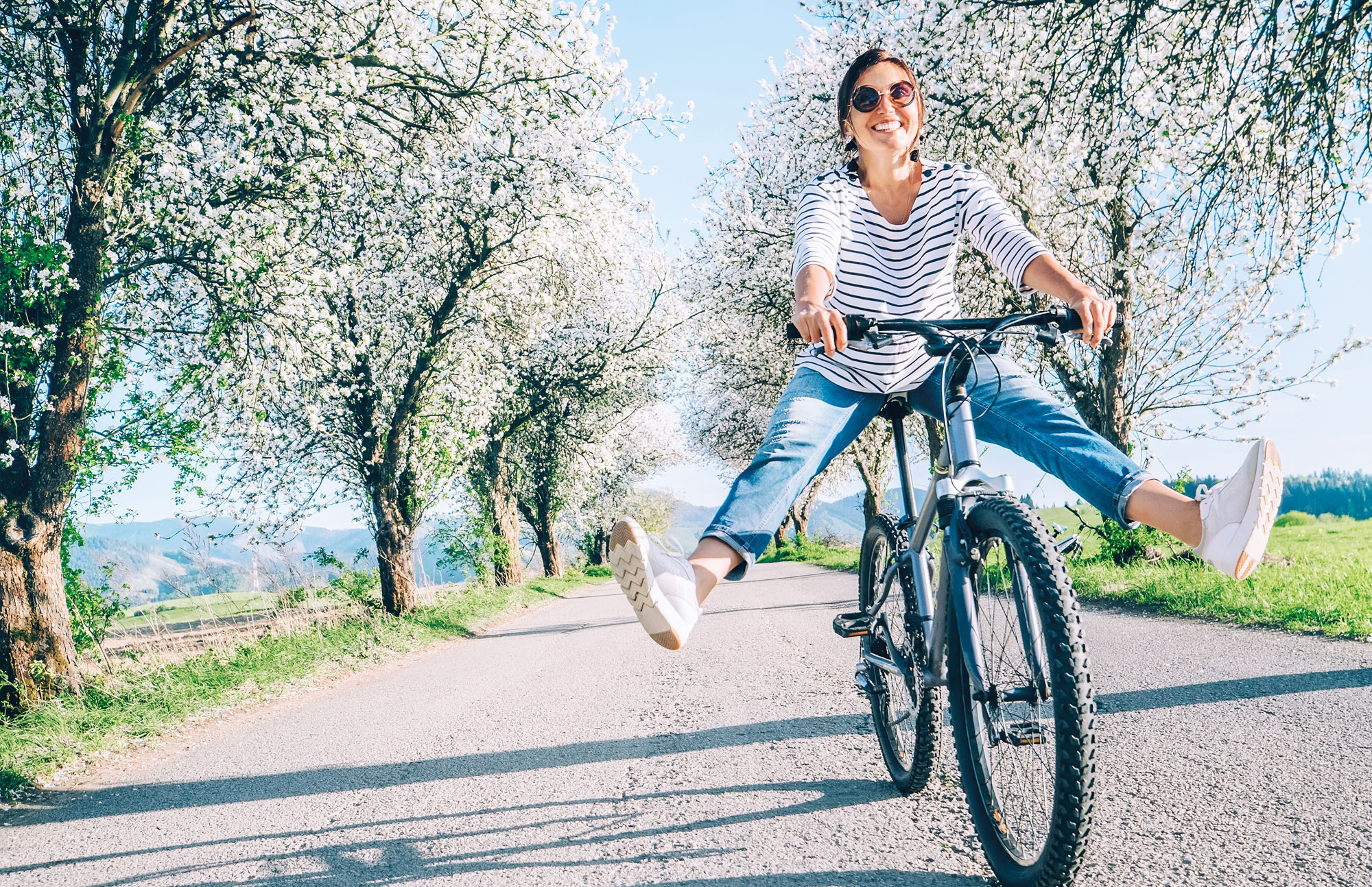 Frau fährt mit dem Fahrrad auf einem Weg im Grünen