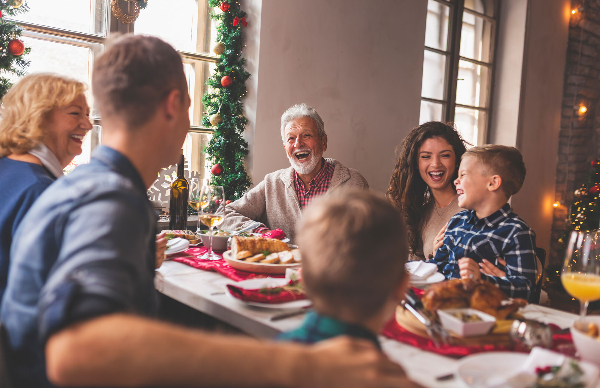 Familie sitzt an festlich gedecktem Tisch und feiert gemeinsames Weihnachtsessen.