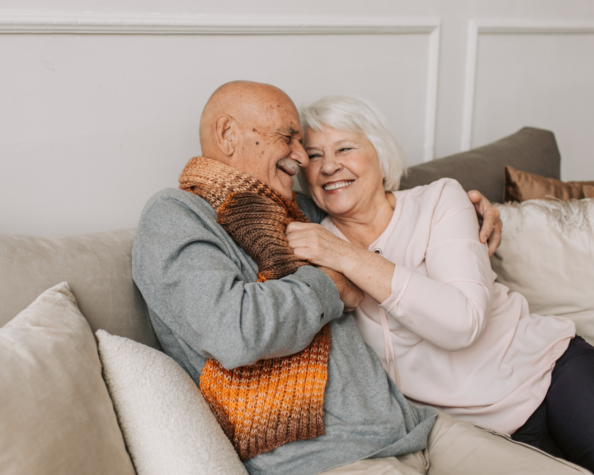 Älteres Paar umarmen sich auf einer Couch